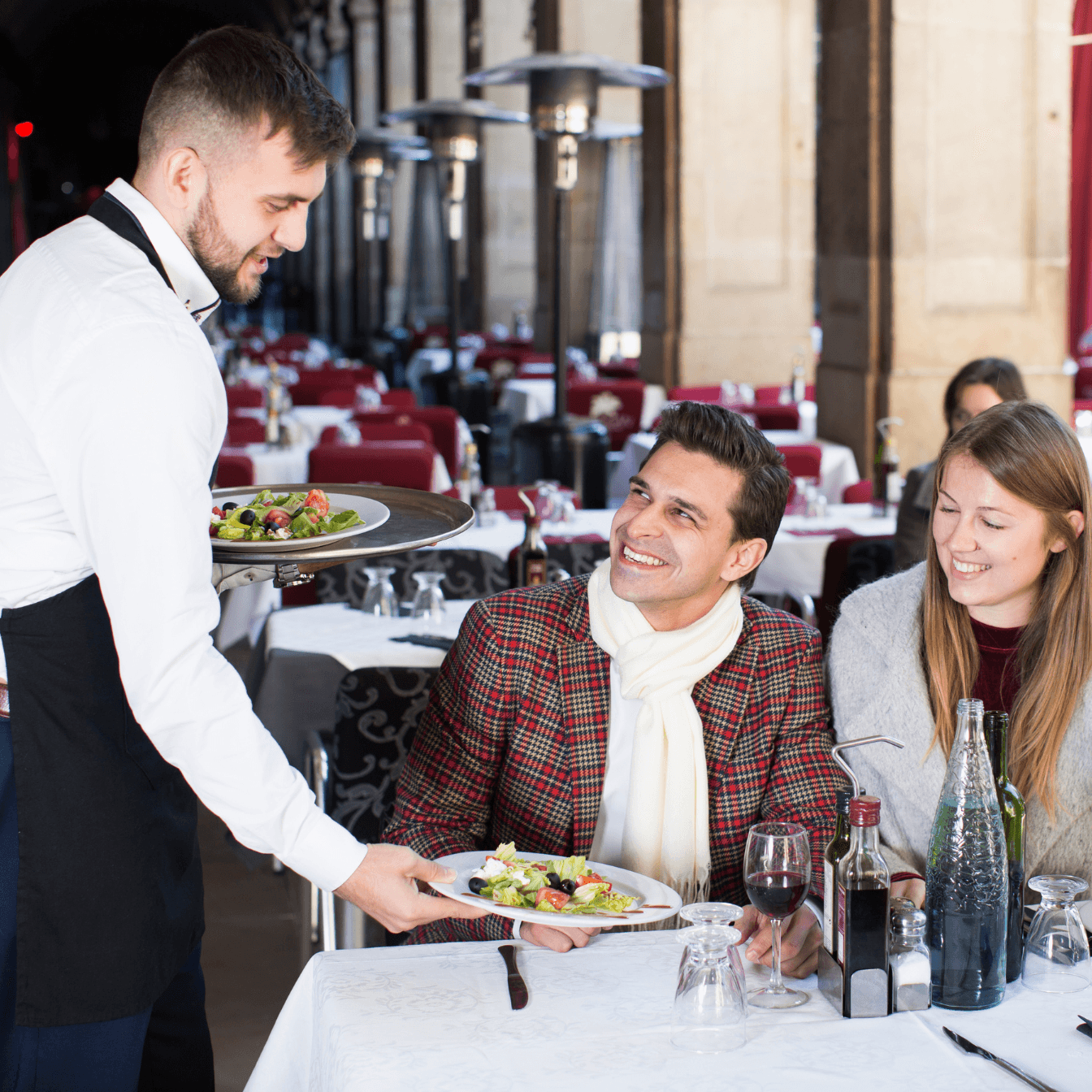 A waiter serving a table at an outdoor restaurant